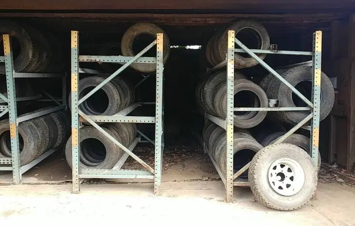 A couple of metal shelves with tires stacked on top.