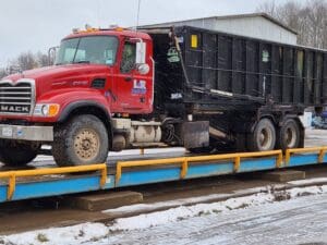 A red truck is on the trailer with a black dump truck.